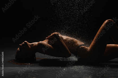 Girl with a beautiful figure on a black cyclorama under the shower