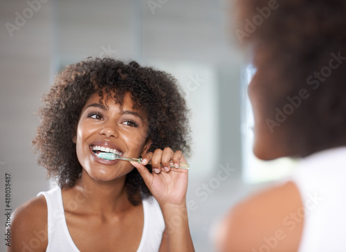 Принти на полотні Keeping her smile. Shot of a a young woman brushing her teeth.