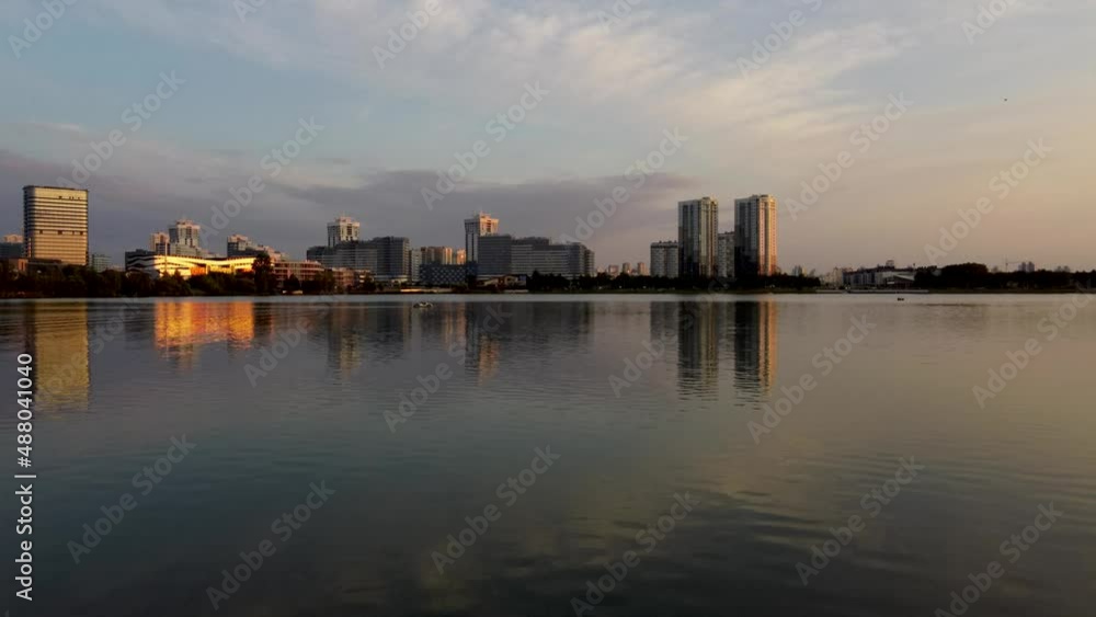 Modern neighbourhood reflects in water of drozdy water lake on sunset, aerial flying towards them, Minsk, Belarus, sunset on a summer day. Modern neighbourhood reflects in water of drozdy water lake on sunset, aerial flying towards them, Minsk, Belarus, sunset on a summer day.