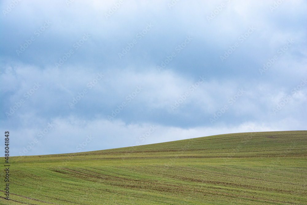 a deep blue sky over a green field on a hill