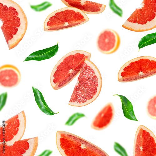 Background of grapefruit pieces and green leaves on a white background.