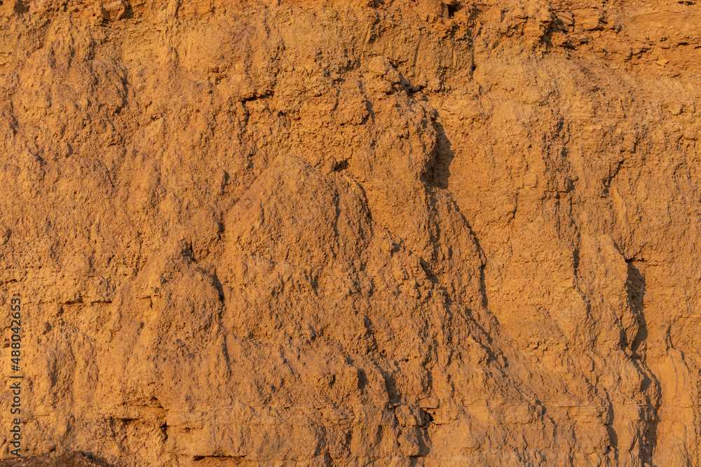Cliff surface of yellow-orange color with a cave.  Texture for background.