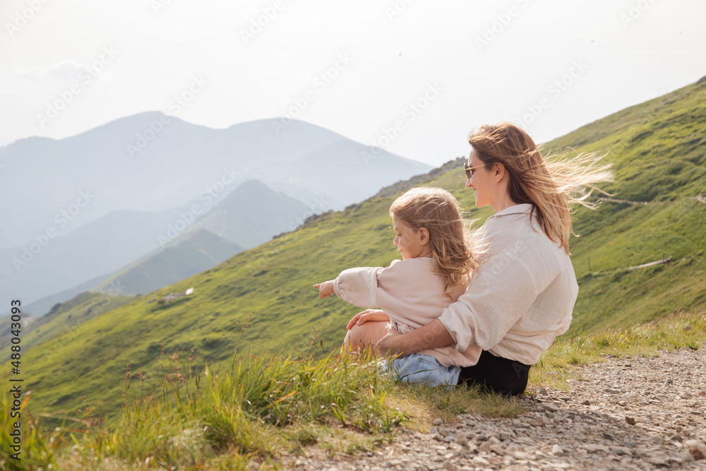 Mother and daughter sitting on the mountain and enjoy the view.