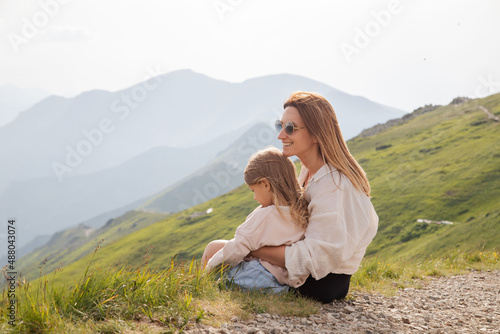 Mother with daughter sitting in mountains. Active family lifestyle.