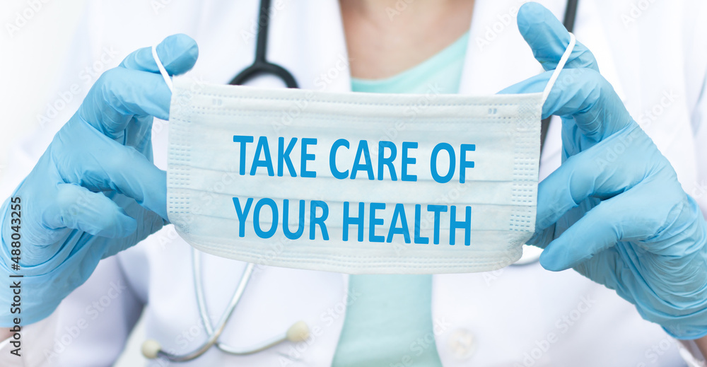 take care of your health text on a protective mask in the hands of a doctor take care of your health text on a protective mask in the hands of a doctor