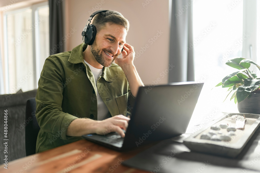 young man worker employee with wireless headphones and laptop in front of is office table young man worker employee with wireless headphones and laptop in front of is office table