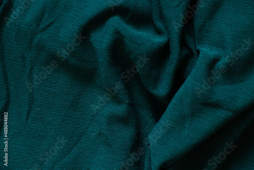 dark green crumpled knitted fabric as background close-up