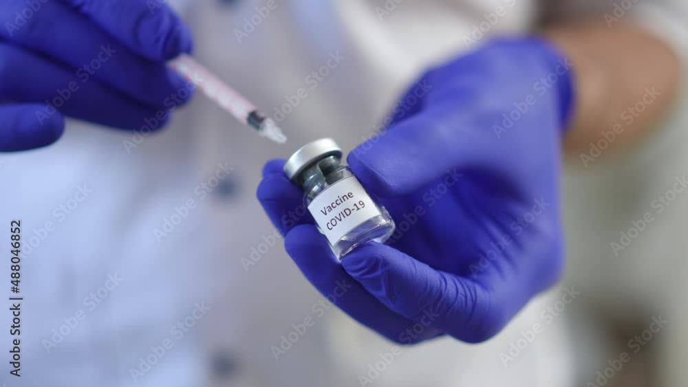 Male hands filling syringe with Covid-19 vaccine in slow motion close-up. Unrecognizable Caucasian man in medical gloves preparing injection for coronavirus vaccination in clinic hospital Male hands filling syringe with Covid-19 vaccine in slow motion close-up. Unrecognizable Caucasian man in medical gloves preparing injection for coronavirus vaccination in clinic hospital