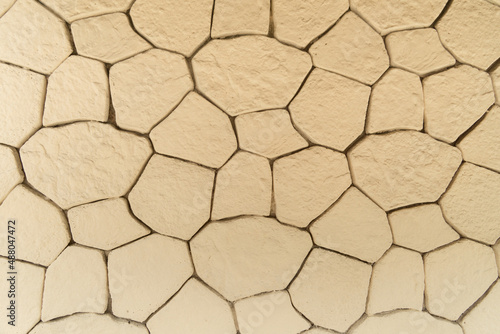 Abstract beige background. Cracks in the form of a grid on a stone wall. Cracked background.