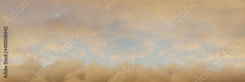 panoramic view to soft yellow sky with fluffy clouds and crescent moon
