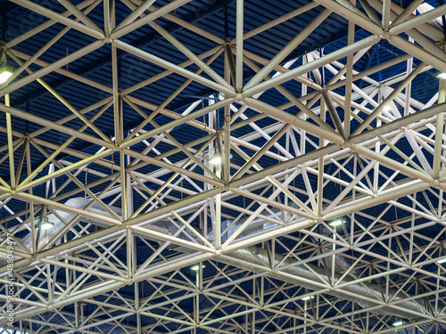 Beam metal structures with spotlights on a blue ceiling in a large building