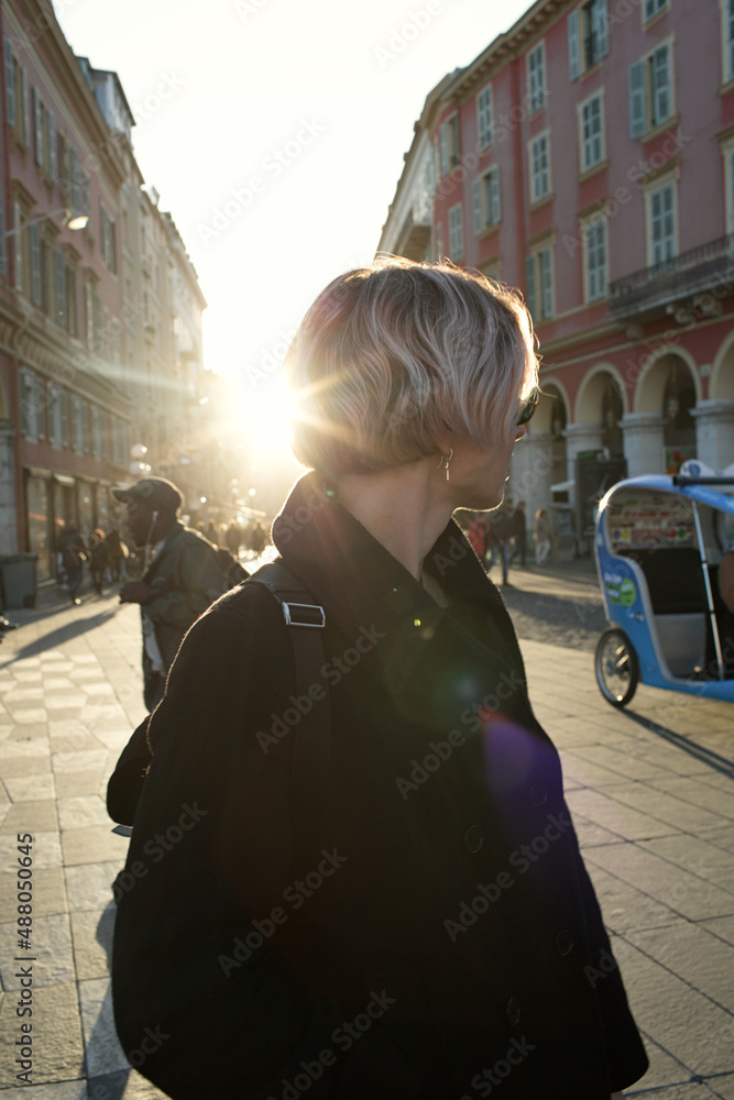 Pretty young woman with short blonde hair and laughing walking in the old city.