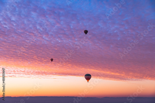 Hot air balloons flying over the Valley of the Kings during an amazing sunrise in Luxor, Egypt.