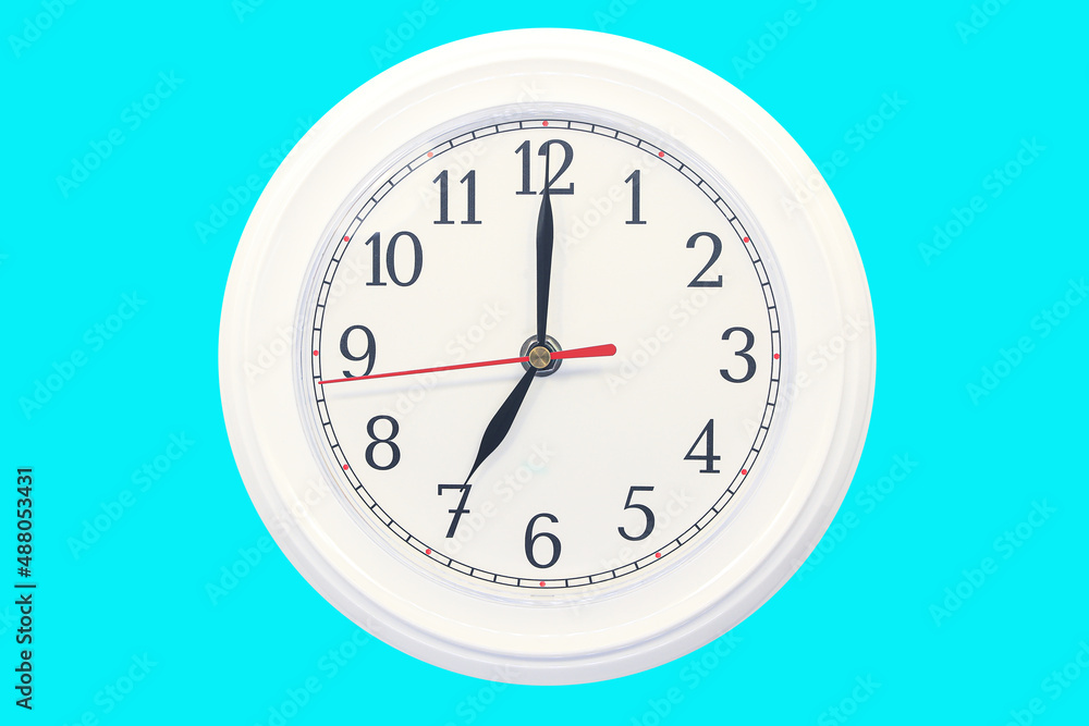 Wall mounted white dial clock isolated on a blue background Wall mounted white dial clock isolated on a blue background
