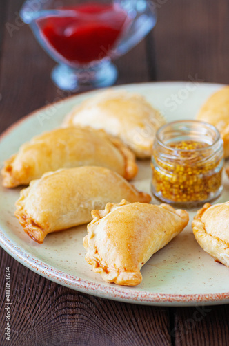 Close up of empanadas on a plate. Wooden background.
