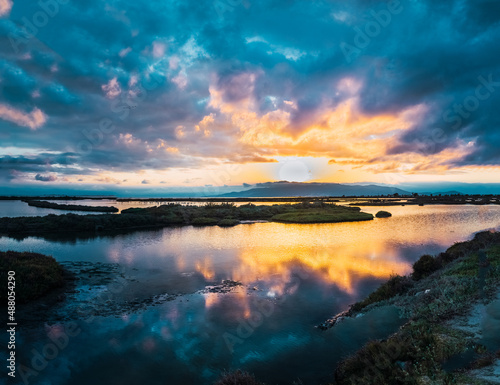 Fototapeta Naklejka Na Ścianę i Meble -  Beautiful sunset with the orb of the sun on the horizon among the clouds over the lagoon.