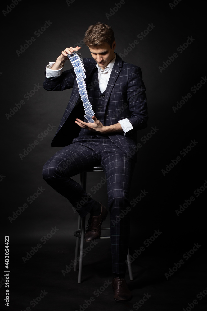 Fototapeta premium Man shows anaconda trick with deck of playing cards. Magician's Performance. Isolated on black background.