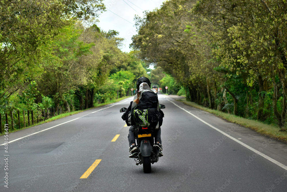couple traveling on vacation on a motorcycle with big suitcases on a road with trees and nature