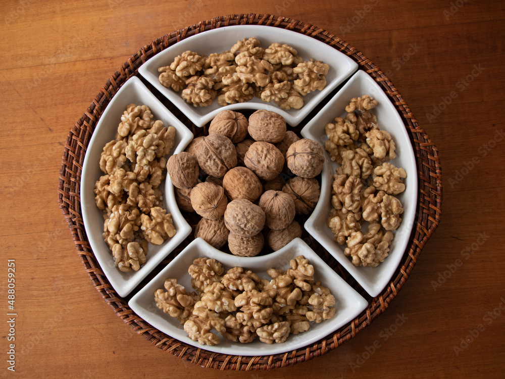 Tray of walnuts in shell and butterflied walnuts taken from above on wooden table Tray of walnuts in shell and butterflied walnuts taken from above on wooden table