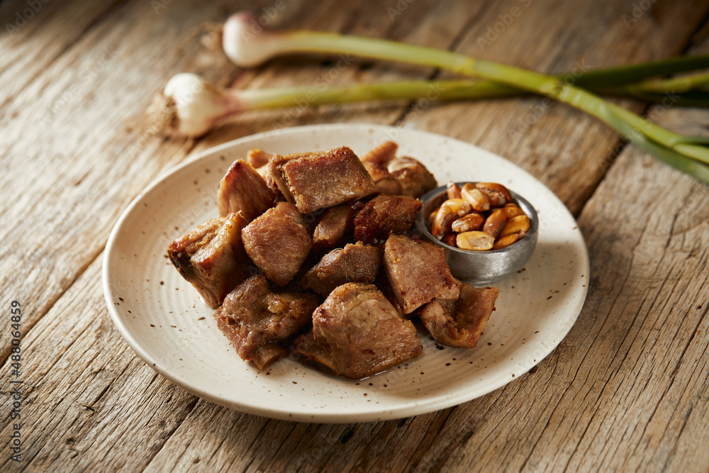 Fototapeta premium Homemade fritada a typical ecuadorian dish that consists on braised pork. It’s served on a white plate with chilli and tostado, with a traditional and wooden background 