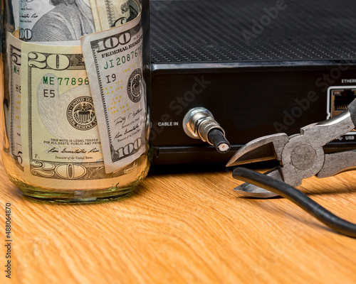 Cable TV cord being cut with cash money. Cord cutting, wireless, streaming television concept.