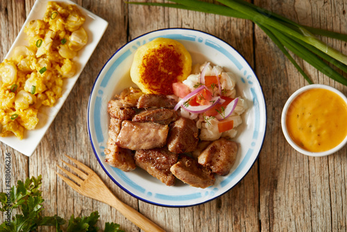 Homemade fritada a typical ecuadorian dish that consists on braised pork. It’s served on a white plate with motepillo and with a traditional and wooden background 