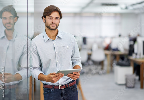 Hes a confident young businessman. Portrait of a handsome young businessman standing in his office. photo