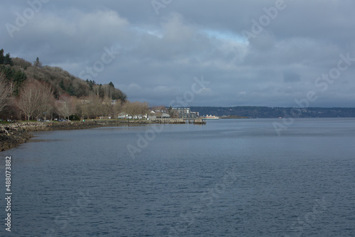 Photograph of a fishing pier, restaurants, buildings, and a ferry on the Puget Sound in Tacoma, Washington.