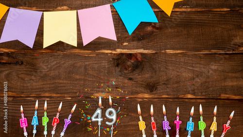 Top view, birthday decorations from letters of candles with fire and festive garlands, save space. Happy birthday background with number 49 on a brown board table. happy birthday for forty nine photo