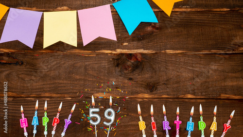 Top view, birthday decorations from letters of candles with fire and festive garlands, save space. Happy birthday background with number 59 on a brown board table. happy birthday for fifty nine photo