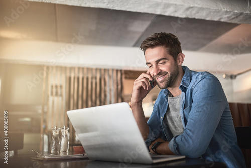 The perfect place for some productivity. Shot of a handsome young man using a laptop and phone in a coffee shop.