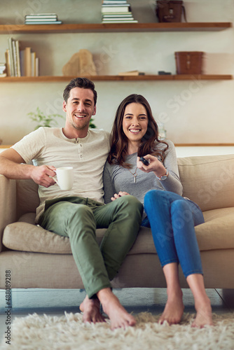 Movie date on the home front. Portrait of a happy young couple relaxing on the sofa and watching tv together.