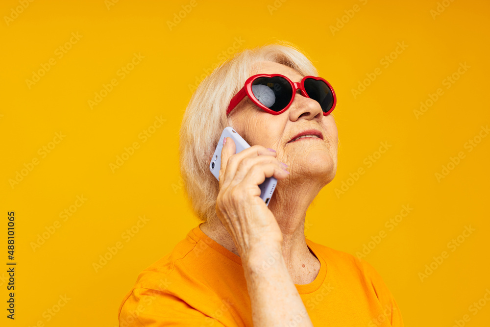 Portrait of an old friendly woman in dark glasses talking on the phone isolated background Portrait of an old friendly woman in dark glasses talking on the phone isolated background
