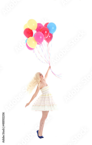  Full length portrait of blonde girl wearing party dress, holding bunch of colourful balloons. Isolated on white studio background