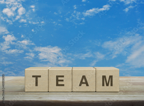 TEAM letter on wood block cubes on wooden table over blue sky with white clouds, Business teamwork communication concept