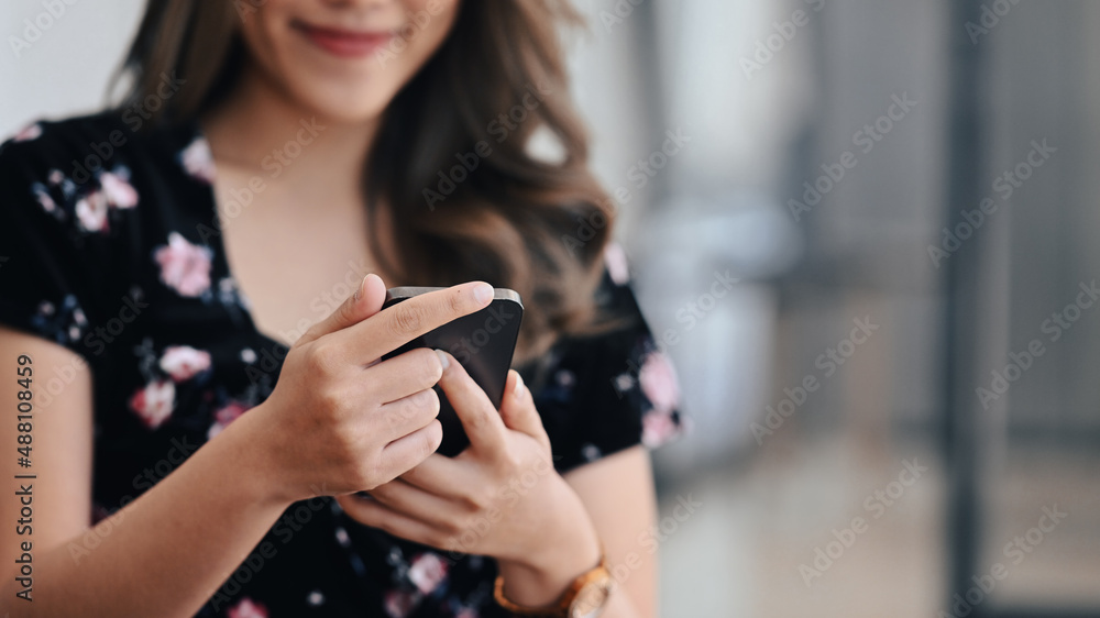 Pleasant happy young woman using smart phone while sitting in office. Pleasant happy young woman using smart phone while sitting in office.