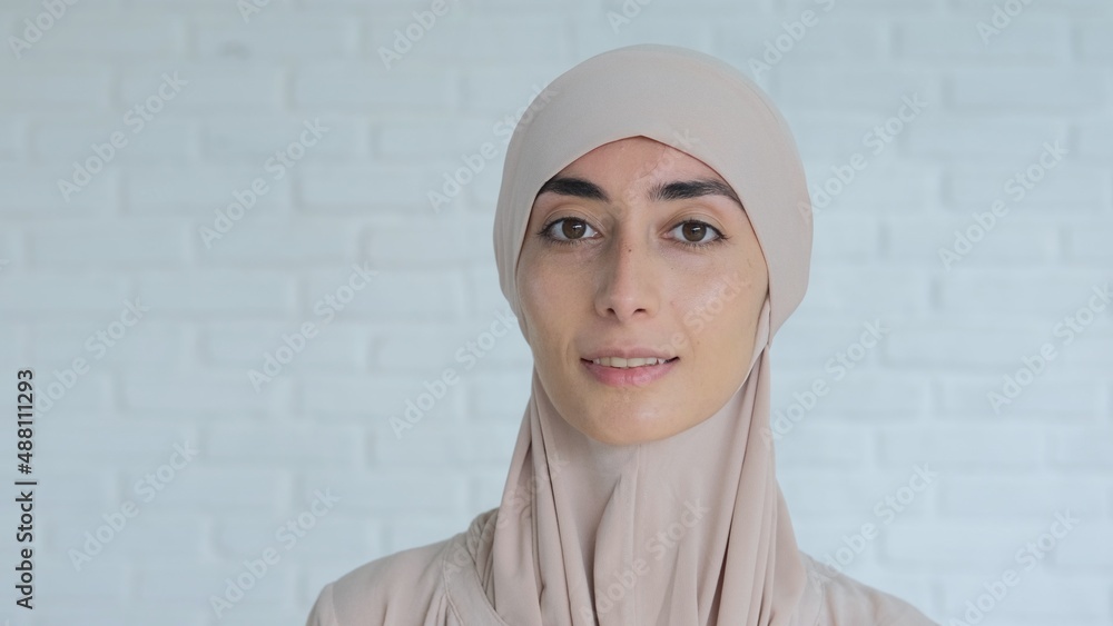 Portrait of smiling muslim woman wearing traditional hijab head covering looking confidently at camera