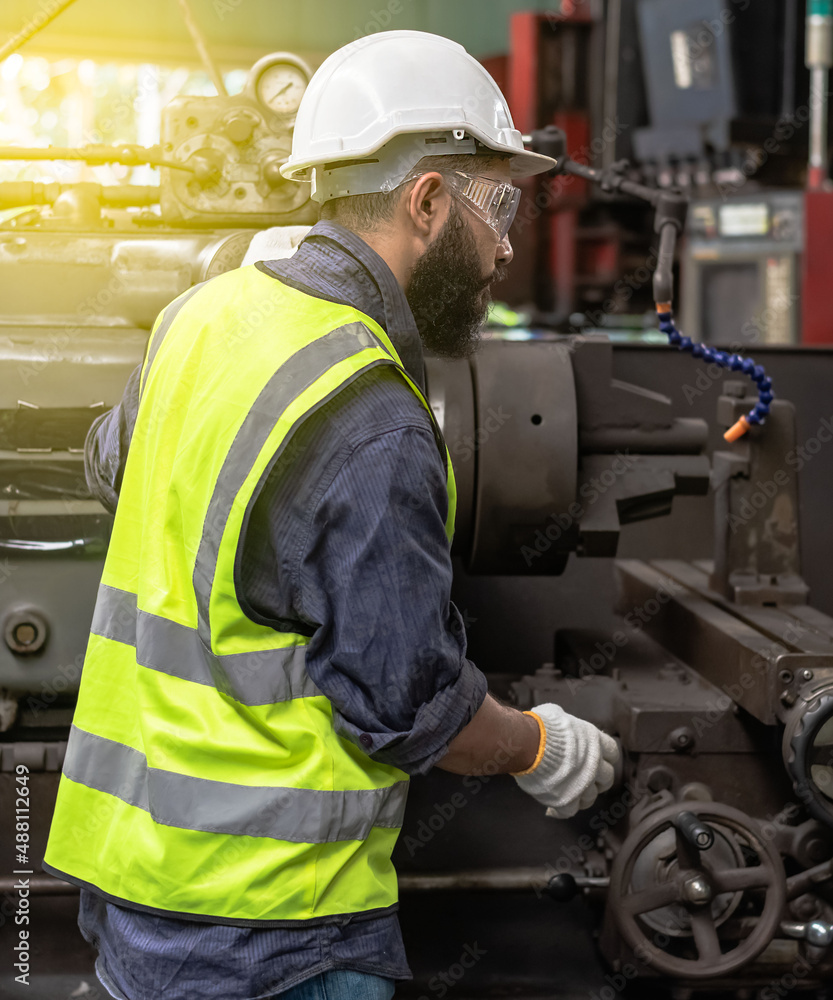Engineer wearing safety helmet and vest working with heavy machinery in industrial factory Engineer wearing safety helmet and vest working with heavy machinery in industrial factory