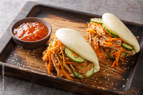 Street food bao sandwiches with pulled pork and vegetables close-up on a wooden tray on the table. horizontal photo
