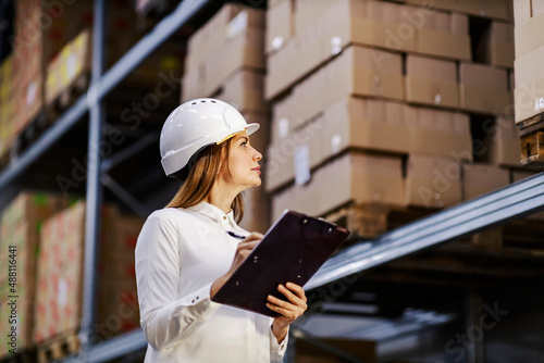 A businesswoman with chart make an inventory at warehouse.