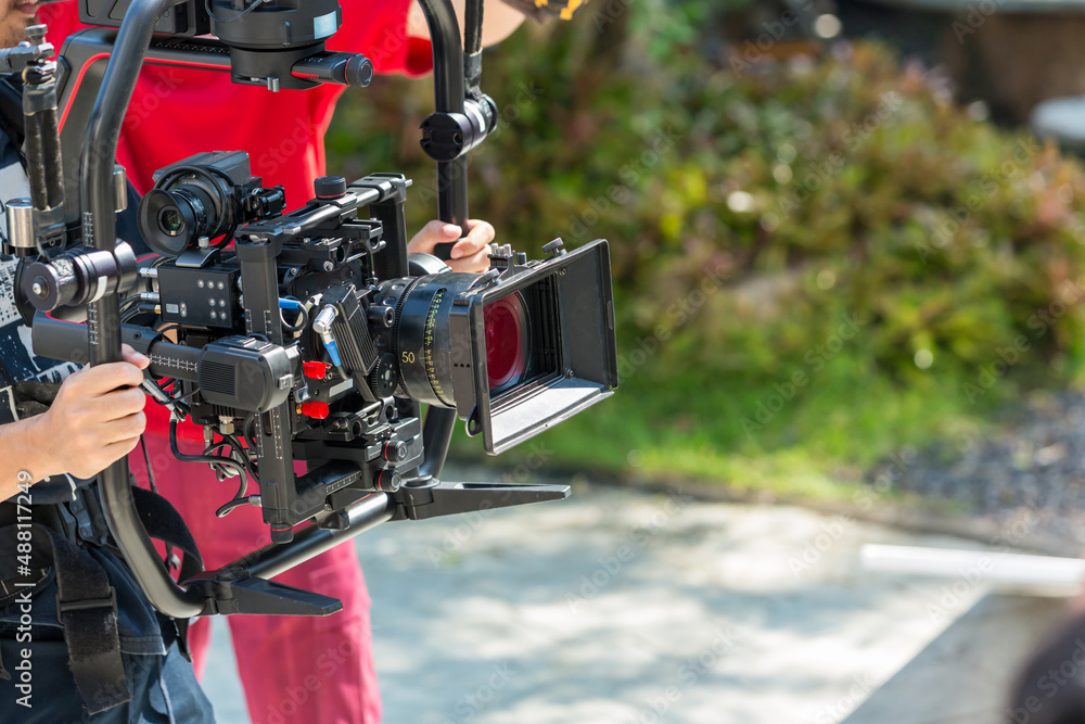 Movie shooting or video production and film crew team with camera equipment. Video camera operator working with equipment. Director of photography with a camera in his hands on the set Movie shooting or video production and film crew team with camera equipment. Video camera operator working with equipment. Director of photography with a camera in his hands on the set