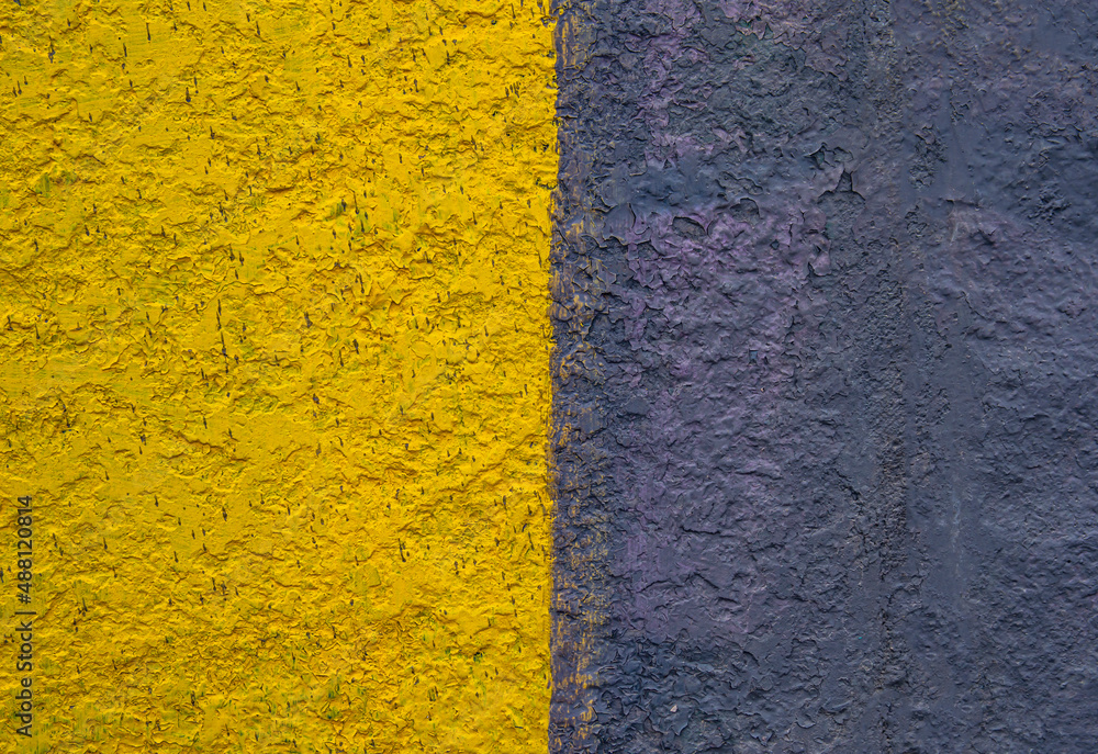 Fototapeta premium The surface is painted in half in yellow and black. Paint on a concrete wall. Texture of a colored surface. Black and yellow color. background image. Template for text. Two vertical halves.