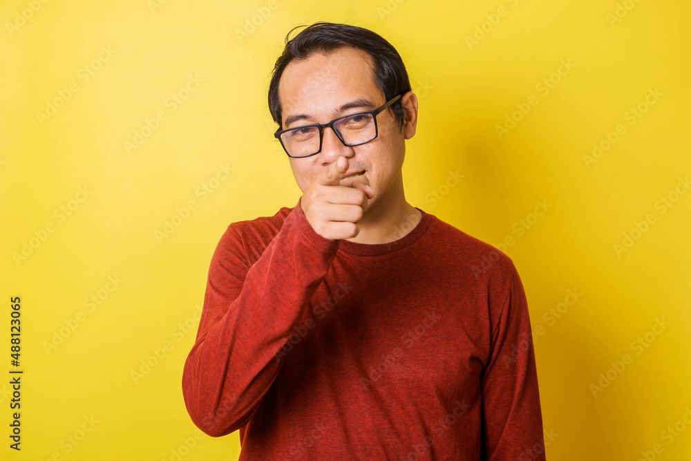 Fototapeta premium Casual man in glasses pointing at camera with index finger, accusing gesture isolated on yellow background