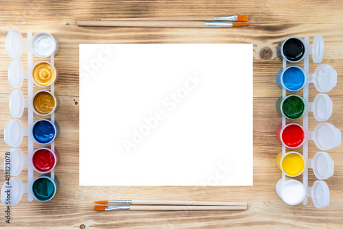 paints and blank sheet on wooden table, flat view, space for text, creativity concept