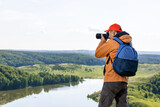  Man traveler takes a photo beautiful summer landscape on professional camera. Healthy active concept.