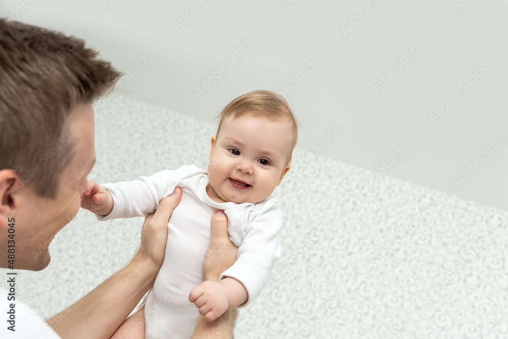 Father throw toss baby up. Playing and laughing. White casual clothes at home. Copy space. Family togetherness concept. Home recreation on weekend Father throw toss baby up. Playing and laughing. White casual clothes at home. Copy space. Family togetherness concept. Home recreation on weekend