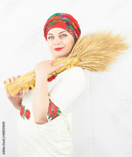 A beautiful Ukrainian woman in traditional folk national costume holds a cult sheaf of wheat - diduch photo