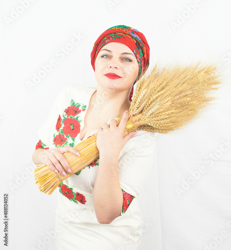 A beautiful Ukrainian woman in traditional folk national costume holds a cult sheaf of wheat - diduch photo