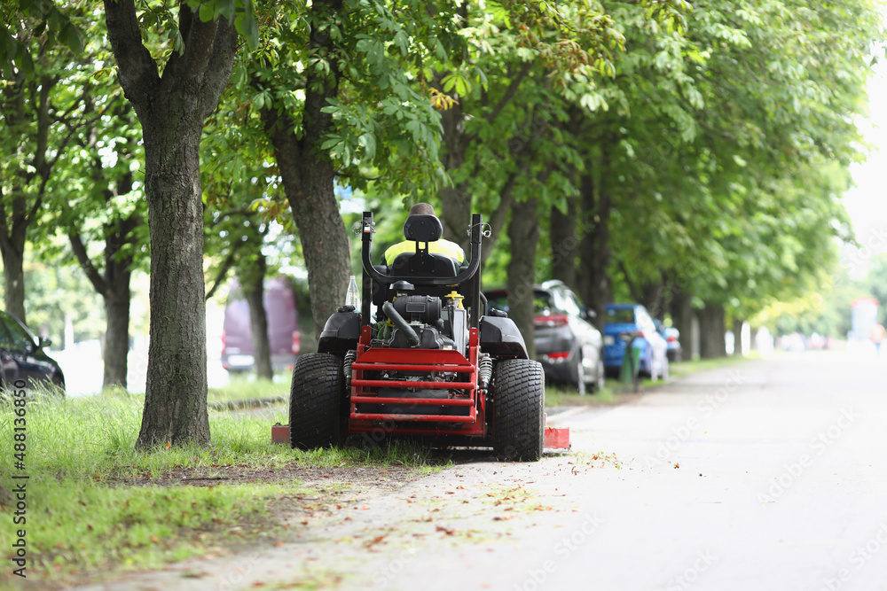 The lawn mower stands on sidewalk near the lawn The lawn mower stands on sidewalk near the lawn