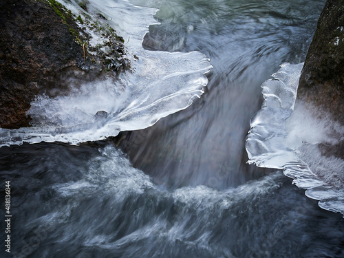 Winter river. Rapid flow of the river through rocks and ice.